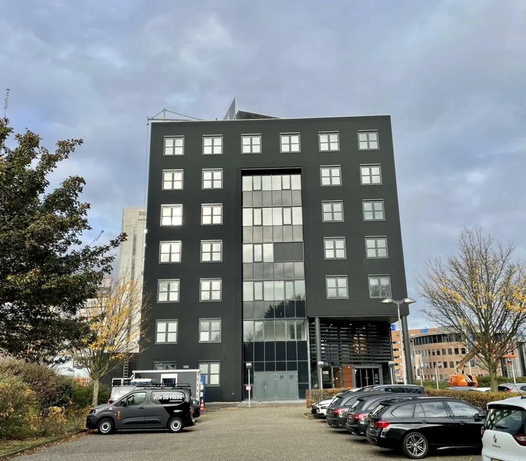 Zwart kantoorgebouw aan het Rivium Quadrant met geparkeerde auto's op de voorgrond.